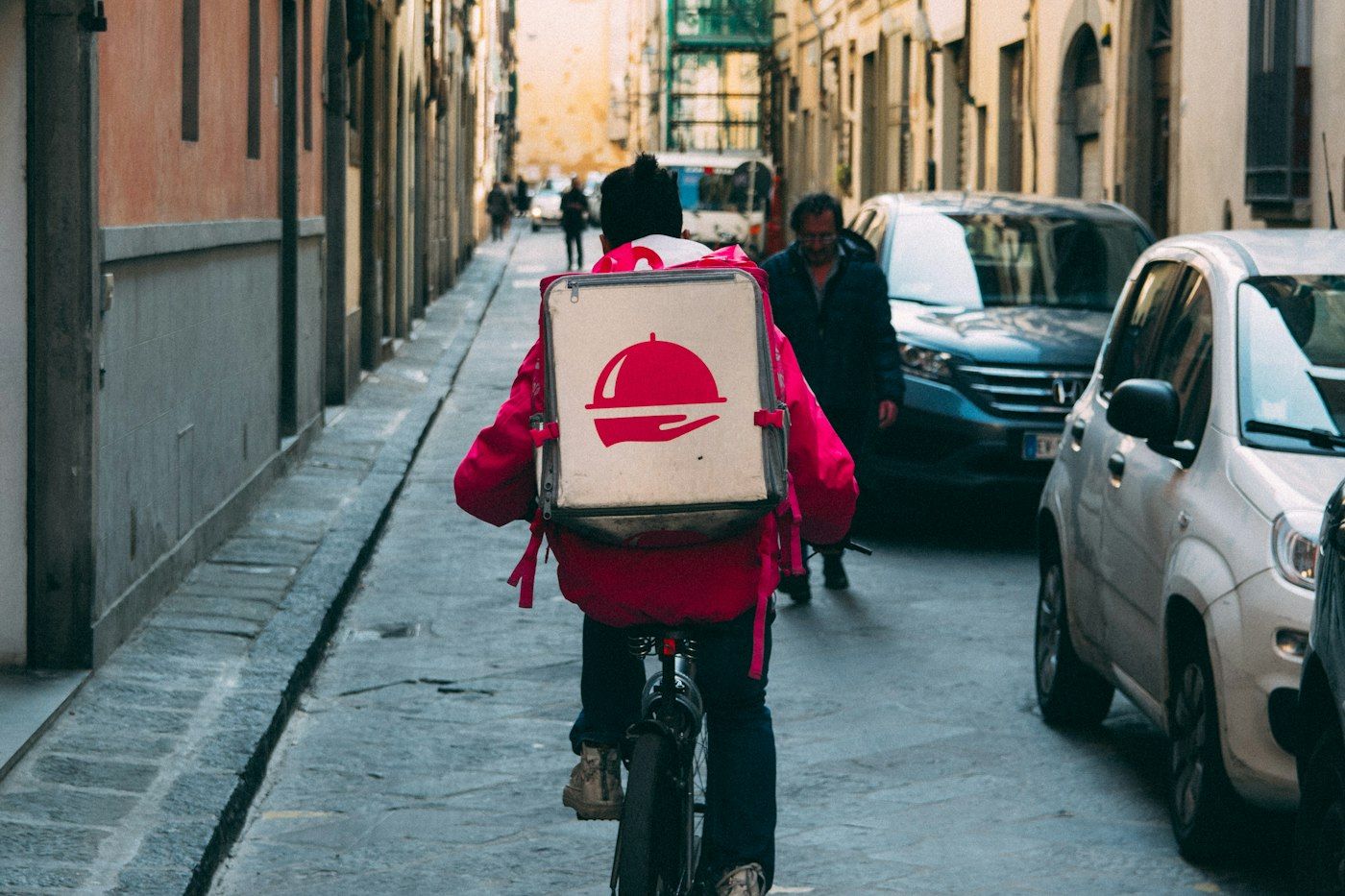 Fattorino in bicicletta con lo zaino per le consegne